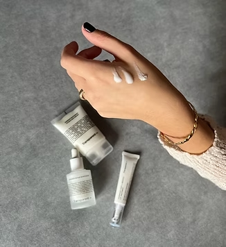 Mano con crema y los productos de fondo